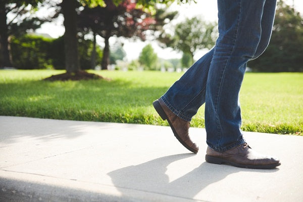 man walking on a sidewalk next to a garden