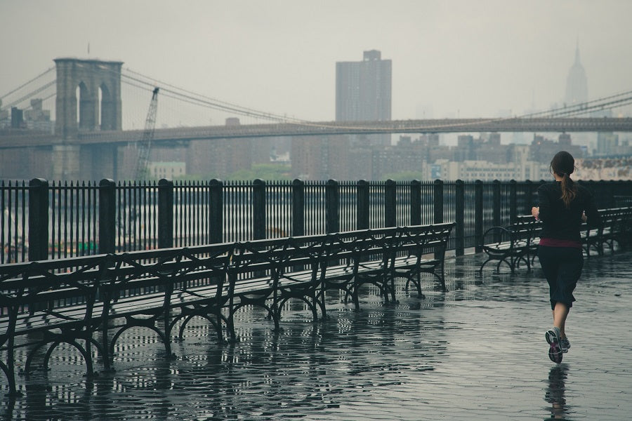 woman running aside a river pier under the rain