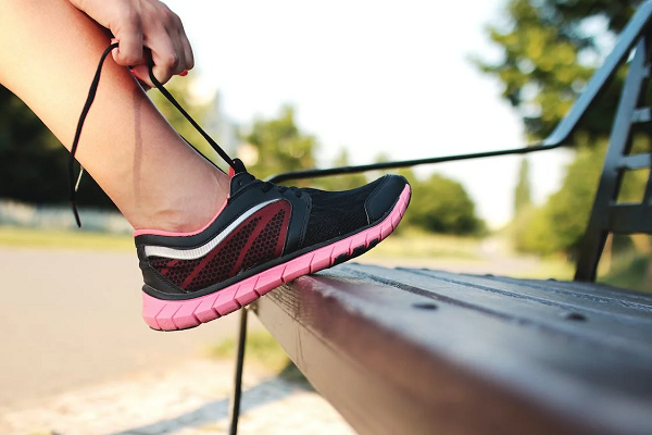 woman’s foot while she ties her shoelace on a bench