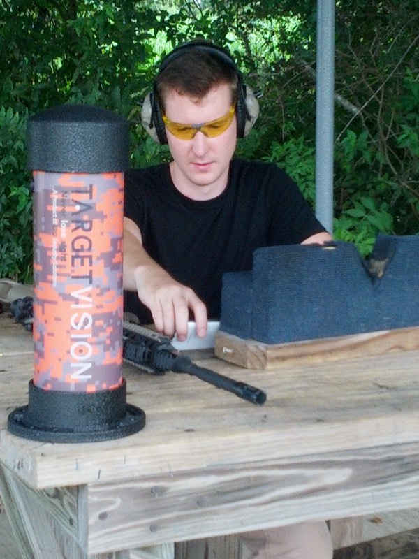 Man sitting at a range table with hearing and eye saftey and the first generation Longshot camera.