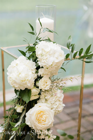 Image of hydrangeas, roses and ranunculus set up for a wedding ceremony on a gold structure