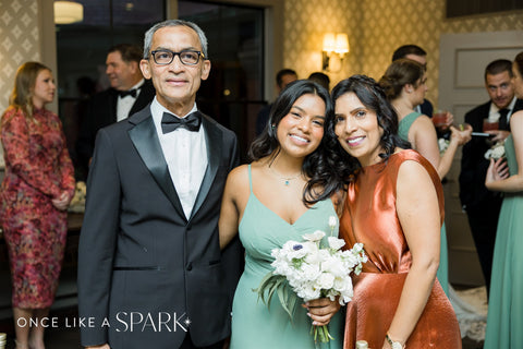 image of bridesmaid in sage green guests holding white and green floral bouquet in between two other wedding guests at the Stevens Estate at Osgood Hill in North Andover, MA