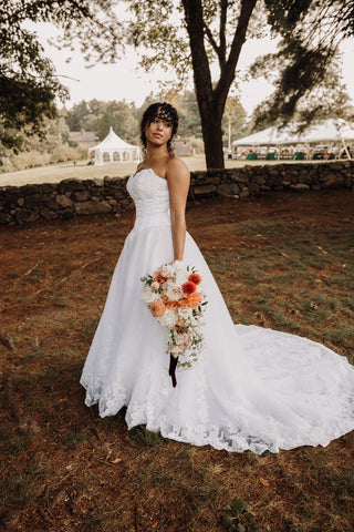 Image of bride at Laurel Springs Farm wedding venue in Massachusetts during her bridal portraits. She is outside and the image showcases her muted pink flower bridal bouquet against her wedding dress.