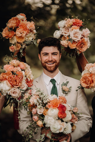 Halo of flower photo with bridesmaids bouquets surrounding groom. The bouques are in muted pink flowers.