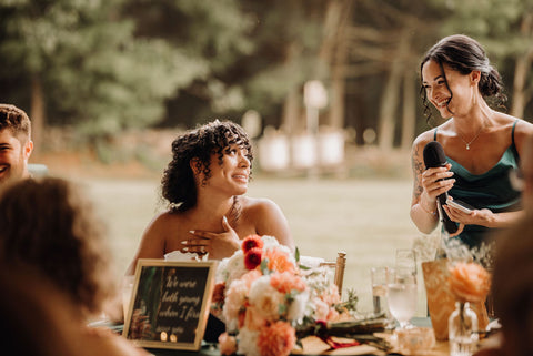 Image of maid of honor giving maid of honor speech with bride looking at her smiling.
