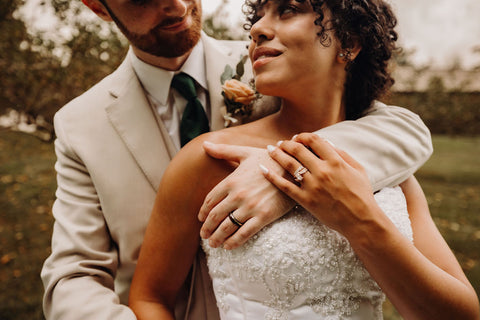 Image of bride and groom and Laurel Springs Farm wedding venue in Massachusetts. The image is a close up of the groom's arm around his bride with her hand touching his.