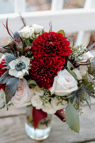 Fall bridal bouquet with deep red dahlias, anemones, creamy white and pale pink roses and greenery.