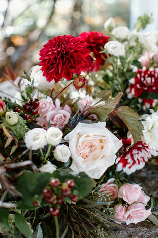 Deep red dahlias, creamy white roses, berries and greenery for floral installation ceremony arch