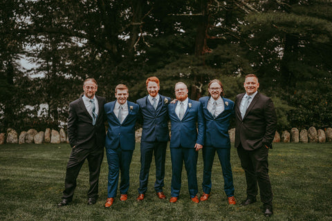 Image of groomsmen and groom in a row looking at the camera. They are in blue suits at the Estate at Moraine Farm.