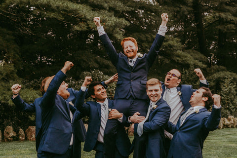 Image of groomsmen holding up groom with arms raised in air.