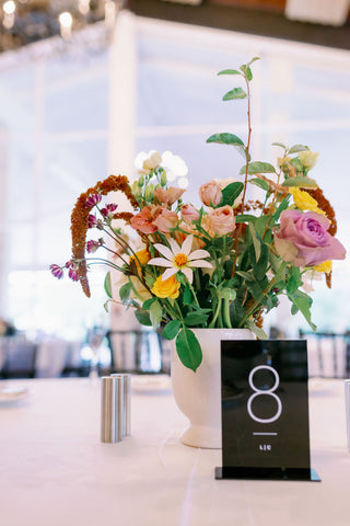 Muted fall color palette table centerpiece at an elegant wedding. Colors include pink, purple, yellow, orange and white.