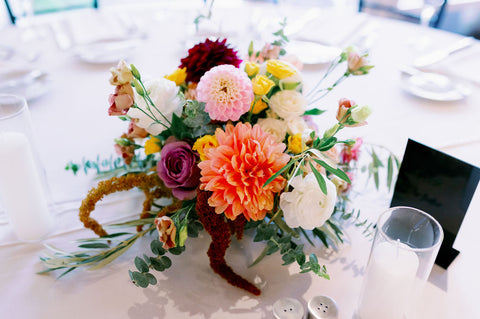 Muted fall colored centerpiece with pink, yellow, orange, purple and white.