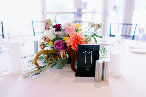 Wedding centerpiece flowers in muted fall color palette including pink, orange, yellow and purple.