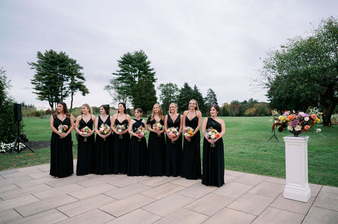 Image of bridesmaids in long black gowns during wedding ceremony at thye outdoor space at the Cape Club of Sharon.