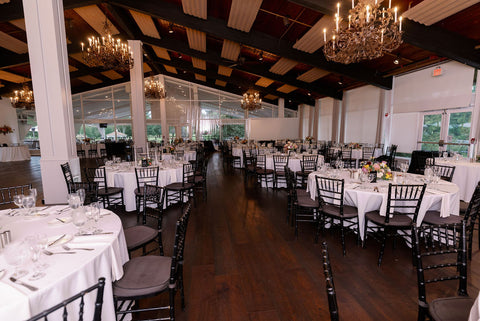 Reception space set up at the Cape Club of Sharon, a Massachusetts wedding venue. The image shows the tabels set up ready for guests. White table cloths, flower centerpiece arrangements.