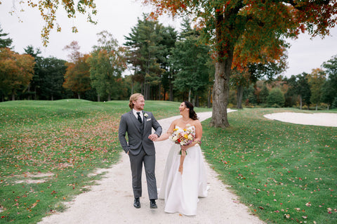 Image of bride and groom walking down path at the Cape Club of Sharon, as part of their wedding portraits.