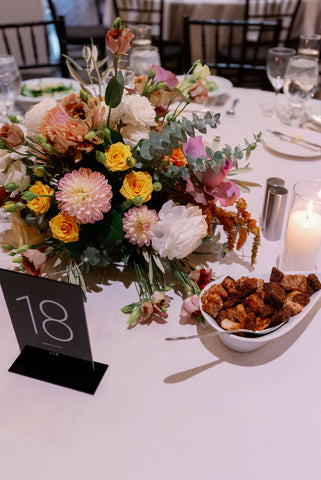 Image of wedding reception table set up with fall floral centerpieces with pinks, yellow, oranges, purples and whites.