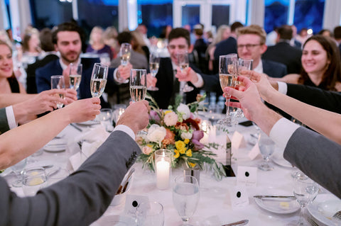 Image of wedding guests raising their glasses for a toast.