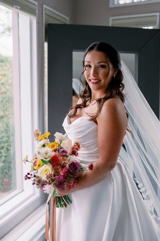 Image of bride holding muted fall color wedding bouquet.