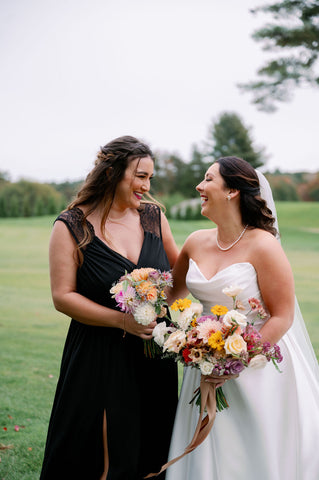 Image of bride and bridesmaid carring bouquets with flowers in muted fall colors.