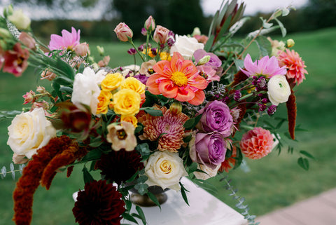 Image of fall wedding ceremony arrangement including dahlias, marigolds, sedum, celosia, ranunculus, lisianthus, mums, leucadendron, asclepia, eucalyptus, and amaranthus.