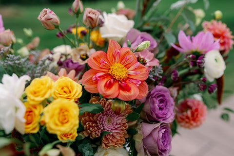 Image of muted fall color ceremony flower arrangement including dahlias, marigolds, sedum, celosia, ranunculus, lisianthus, mums, leucadendron, asclepia, eucalyptus, and amaranthus.
