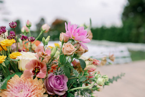 Image of fall wedding ceremony flowers including dahlias, marigolds, sedum, celosia, ranunculus, lisianthus, mums, leucadendron, asclepia, eucalyptus, and amaranthus.