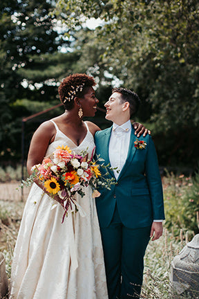 Image of couple on their wedding day. The bride is carrying a joyful floral bouquet in bright colors. 