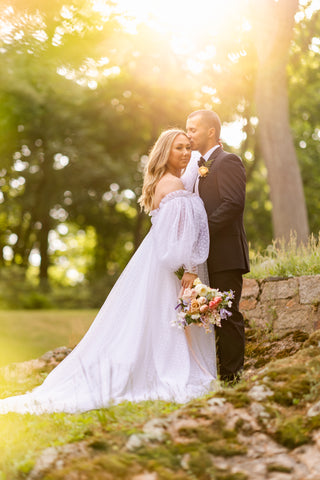 Wedding couple with fairytale vibes. Bride is wearing a romantic wedding dress with puffy sleeves, carrying a dreamy bouquet with pink, off white and purple flowers 