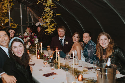 Wedding reception at the Herb Lyceum greenhouse at night. Photo of bride, groom and guests at table.