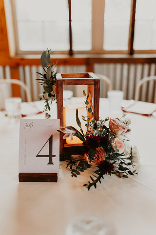 image of wedding table centerpiece at rusrtic elegeant wedding. The centerpiece is a lantern with floral accents.