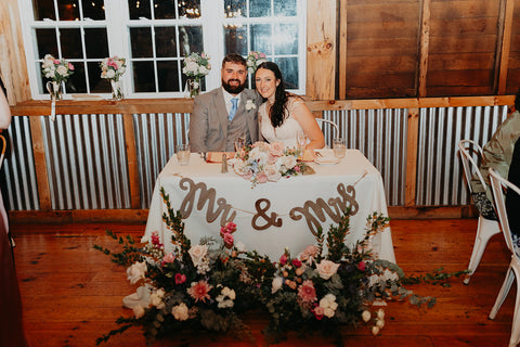 image of bride and groom at their sweetheart table at their rustic elegant wedding.