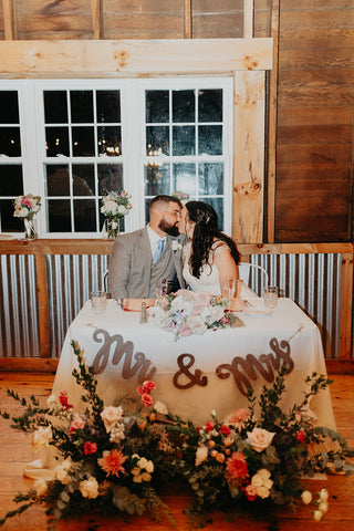 Picture of bride and groom at the sweetheart table at their rustic elegant wedding.