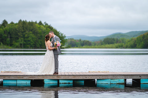 Couple in wedding attire on dock over lake at Camp Lenox in the Berkshires, Massachusetts