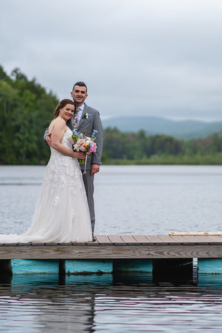 Couple in wedding attire on dock over lake at Camp Lenox in the Berkshires, Massachusetts