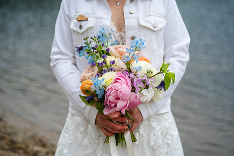 Bride in wedding dress with colorful bridal bouquet on dock over lake at Camp Lenox in the Berkshires, Massachusetts