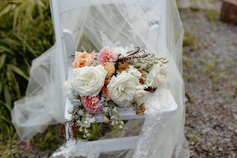 Bridal bouquet with timeless flowers and modern foliage including roses, dahlias, delphinium, dyed grevillea, rice flower, cress, and thistle