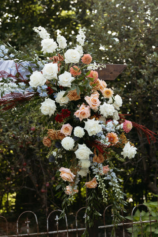 late summer floral wedding arbor with timeless flowers and modern foliage including roes, dahlias, delphinium, dyed grevillea, rice flower, cress and thistle