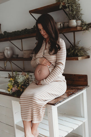 Image of mom to be during a styled maternity photoshoot holding a wild, organic bouqueet of loose white and yellow flowers.