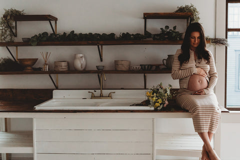 Image of mom to be during a styled maternity photoshoot holding a wild, organic bouqueet of loose white and yellow flowers.