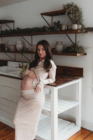 Image of mom to be during a styled maternity photoshoot holding a wild, organic bouqueet of loose white and yellow flowers.