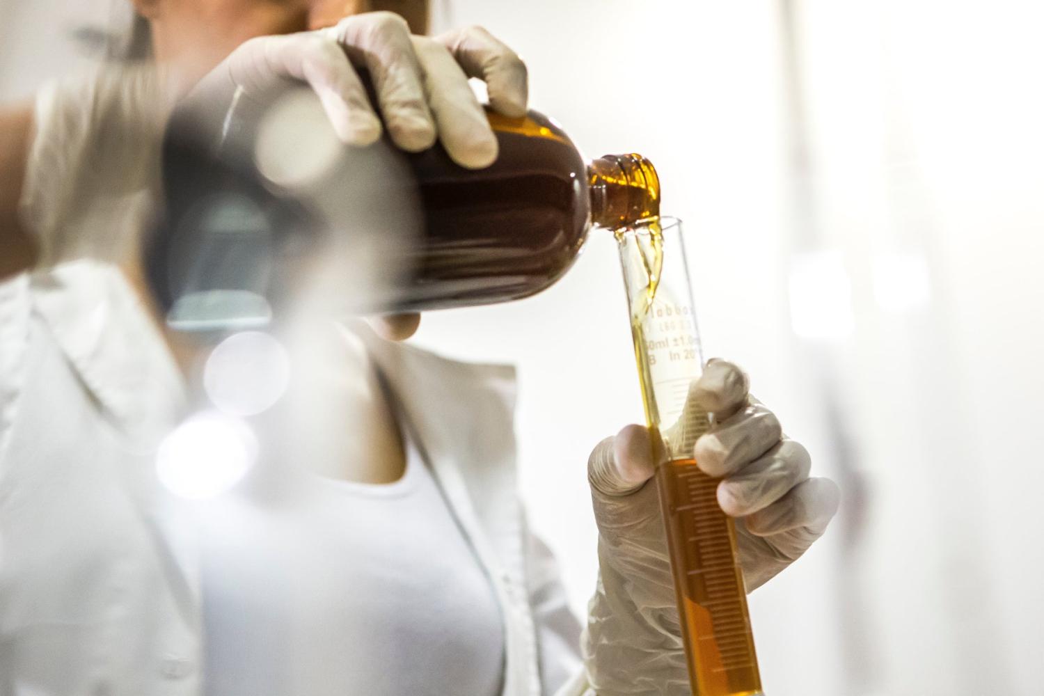 Osoba nalévá tekutinu do ampule v laboratorním prostředí.