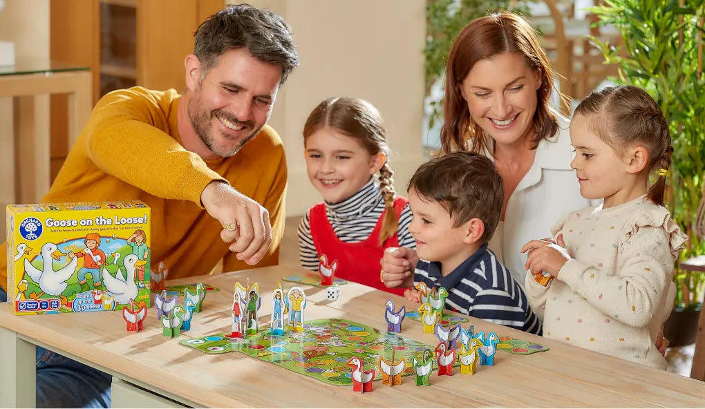 A family enjoys playing the board game 'Goose on the Loose!' together at a table.