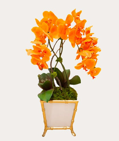 Orange faux orchids in a white cachepot