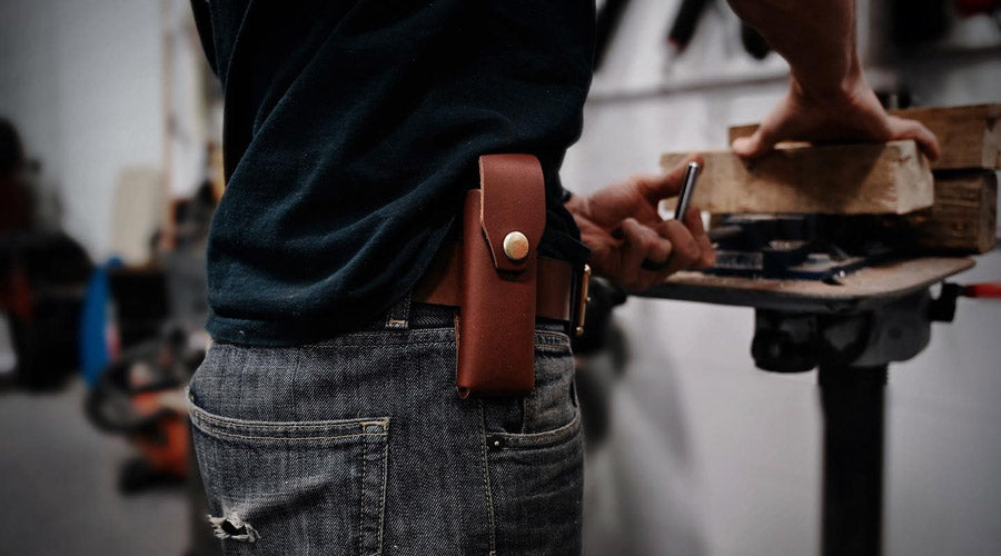 man working on wood, wearing leather belt with sheath