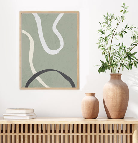 Green line abstract wall art in a natural frame pictured in a neutral living space. 