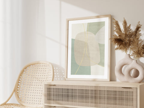Green and neutral abstract wall art in a wooden framed pictured in a neutral living space. 