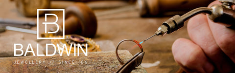 A mans hand holding a soldering iron in the jewellery creation process