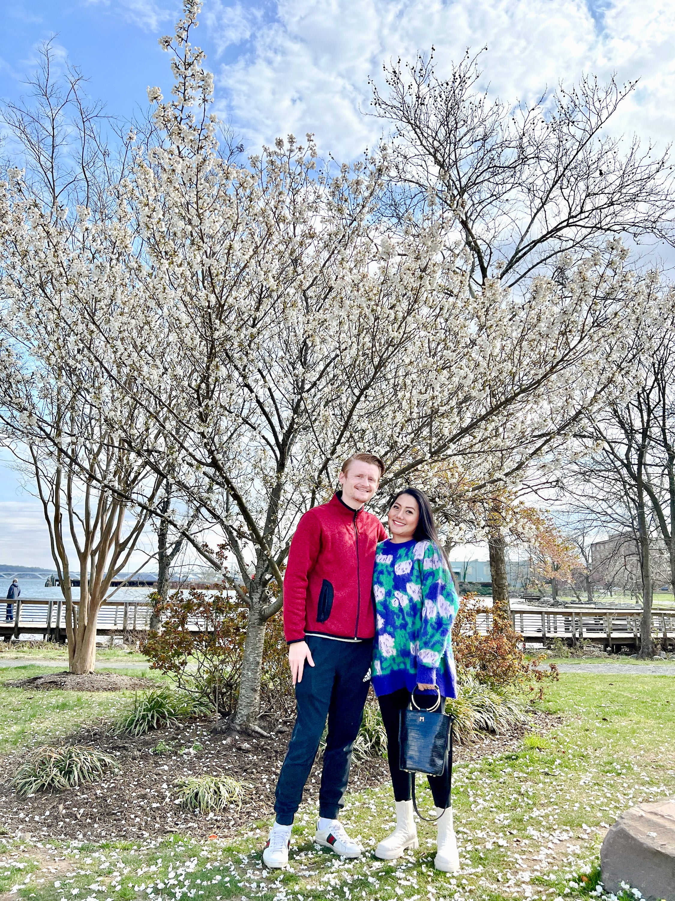 Couple standing in front of blooming cherry blossom tree