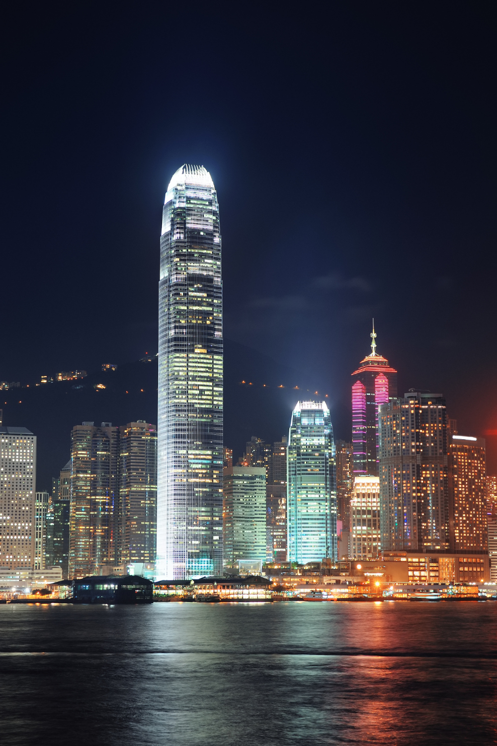 Skyscrapers lit at night off bay in Hong Kong